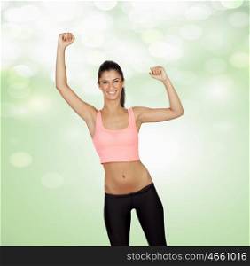Winner attractive girl with sports clothes on a green and bright background