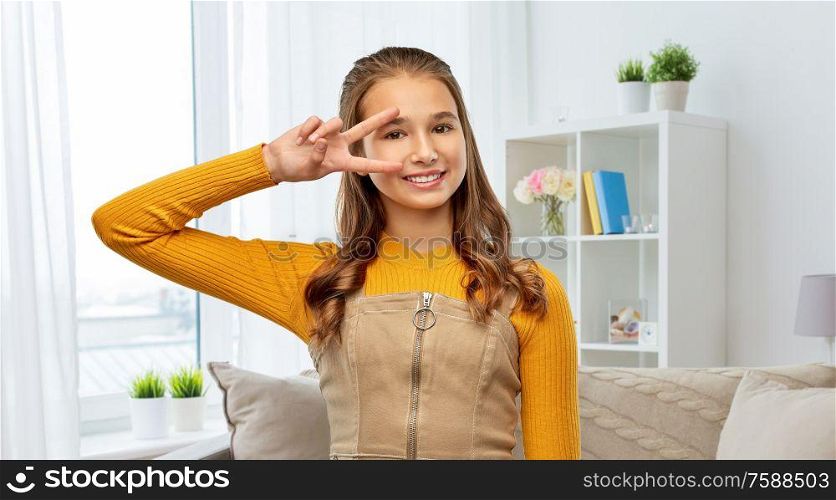 winning gesture, emotions and people concept - happy smiling young teenage girl showing peace hand sign home room background. smiling teenage girl showing peace sign at home