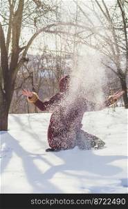 Winter activity scenic photography. Throwing snow in air. Picture of woman with winter forest on background. High quality wallpaper. Photo concept for ads, travel blog, magazine, article. Winter activity scenic photography