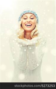 winter, advertisement, christmas and people concept - smiling young woman in winter hat and sweater holding something on her empty palms. woman in winter heat showing empty palms