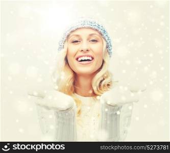 winter, advertisement, christmas and people concept - smiling young woman in winter hat and sweater holding something on her empty palms. woman in winter heat showing empty palms