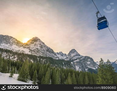 Winter afternoon in the mountains - Winter landscape with evergreen fir forests, the Austrian Alps mountains and a cable car, in Ehrwald municipality, Austria.