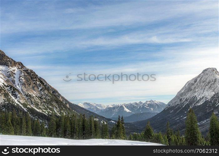 Winter alpine landscape with snowy Alps mountains, green fir forests and a blue sky, in Ehrwald, Austria, in December.