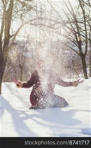 Winter amusement scenic photography. Throwing snow. Picture of woman with winter forest on background. High quality wallpaper. Photo concept for ads, travel blog, magazine, article. Winter amusement scenic photography