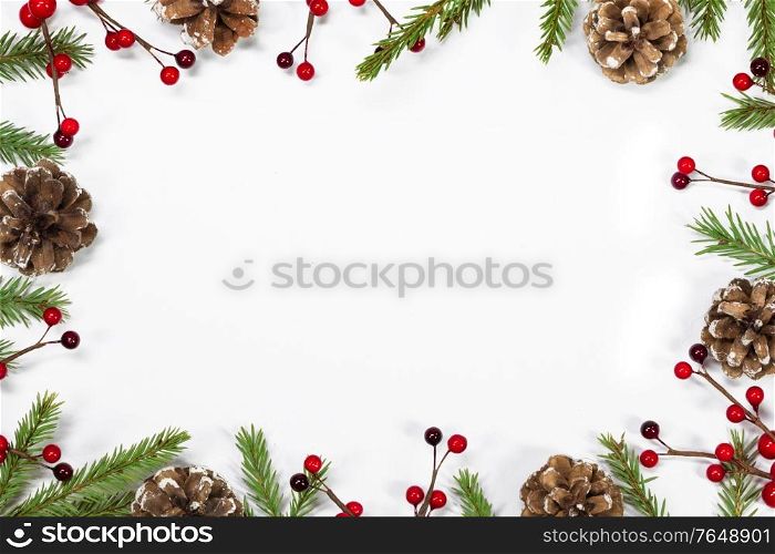 Winter and Christmas frame composition with blank white background, fir tree branch holly berries and pine cones isolated with copy space. Christmas background with decoration