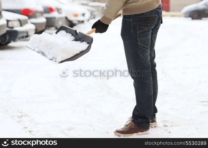 winter and cleaning concept - closeup of man shoveling snow from driveway
