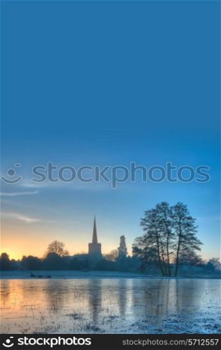 Winter background showing church at sunrise with frosty seasonal landscape.