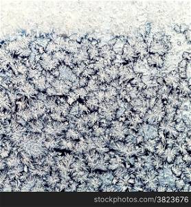 winter background - snowflakes and frost on frozen window pane