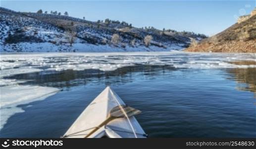 winter canoe paddling - boat bow and partially frozen lake - Horsetooth Reservoir near Fort Collins in Colorado