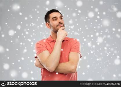 winter, christmas and people concept - man in polo t-shirt thinking over snow on gray background
