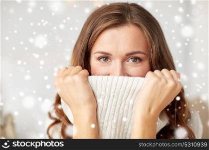 winter, christmas and people concept - young woman or teen girl pulling up pullover collar over snow. young woman or teen girl pulling pullover collar