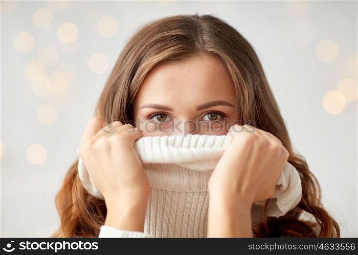 winter, christmas and people concept - young woman or teen girl pulling up pullover collar