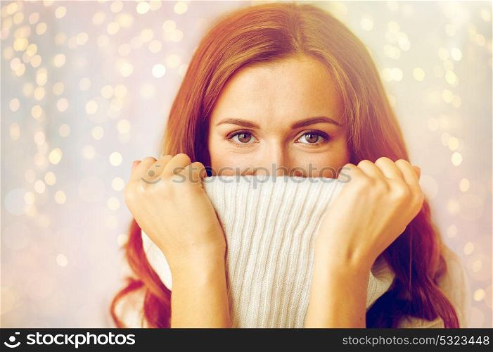 winter, christmas and people concept - young woman or teen girl pulling up pullover collar. young woman or teen girl pulling pullover collar