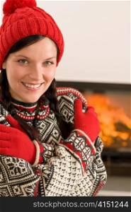 Winter christmas happy woman with hat and gloves by fireplace