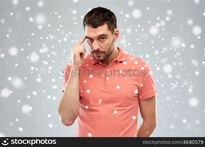 winter, christmas, idea, inspiration and people concept - man pointing finger to his temple over snow on gray background
