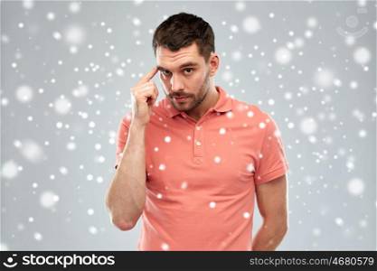 winter, christmas, idea, inspiration and people concept - man pointing finger to his temple over snow on gray background