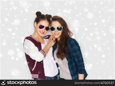 winter, christmas, people and fashion concept - happy smiling pretty teenage girls or friends in sunglasses over gray background and snow