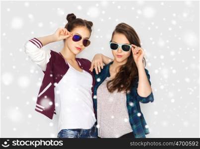 winter, christmas, people and fashion concept - happy smiling pretty teenage girls or friends in sunglasses over gray background and snow