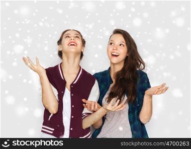 winter, christmas, people and holidays concept - happy smiling pretty teenage girls or friends over gray background and snow. happy smiling pretty teenage girls having fun