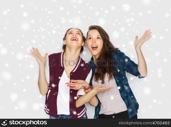 winter, christmas, people and holidays concept - happy smiling pretty teenage girls or friends over gray background and snow