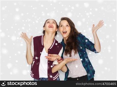 winter, christmas, people and holidays concept - happy smiling pretty teenage girls or friends over gray background and snow