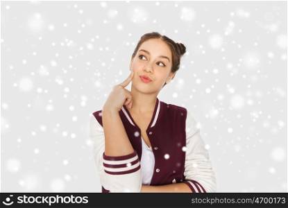 winter, christmas, people and teens concept - happy pretty teenage girl thinking over gray background and snow