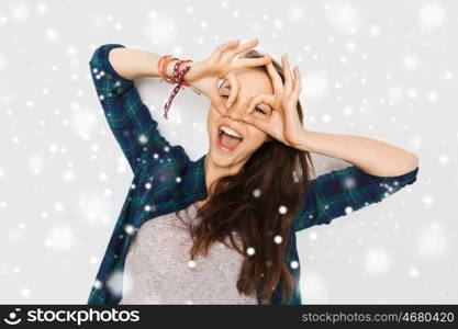 winter, christmas, people and teens concept - happy smiling pretty teenage girl making face and having fun over gray background and snow