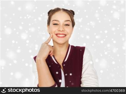 winter, christmas, people and teens concept - happy smiling pretty teenage girl with eye makeup over gray background and snow