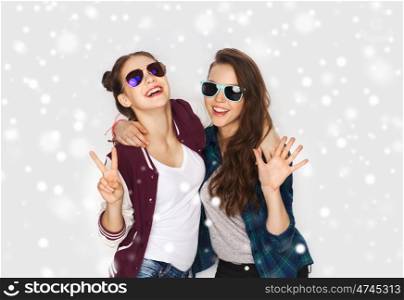 winter, christmas, people, fashion and gesture concept - happy smiling pretty teenage girls or friends in sunglasses showing peace hand sign over gray background and snow