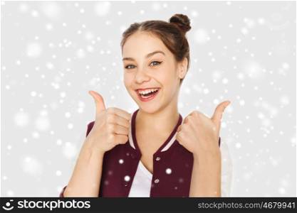 winter, christmas, people, gecture and teens concept - happy smiling pretty teenage girl showing thumbs up over gray background and snow