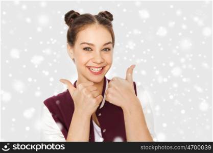 winter, christmas, people, gesture and teens concept - happy smiling pretty teenage girl showing thumbs up over gray background and snow