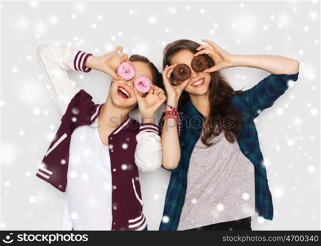 winter, christmas, people, holidays and fast food concept - happy smiling pretty teenage girls or friends with donuts making faces and having fun over gray background and snow