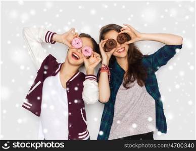 winter, christmas, people, holidays and fast food concept - happy smiling pretty teenage girls or friends with donuts making faces and having fun over gray background and snow