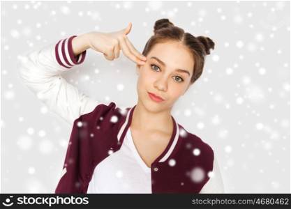 winter, christmas, people, stress and gesture concept - bored teenage girl making headshot by finger gun gesture over gray background and snow