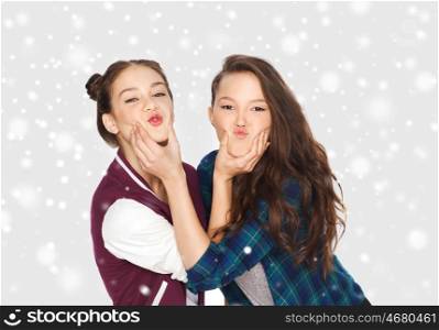 winter, christmas, people, teens and friendship concept - happy smiling pretty teenage girls or friends having fun and making faces over gray background and snow