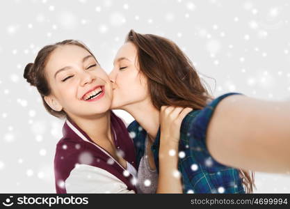 winter, christmas, people, teens and friendship concept - happy smiling pretty teenage girls or friends taking selfie and kissing over gray background and snow