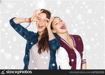 winter, christmas, people, teens and friendship concept - happy smiling pretty teenage girls or friends having fun and making faces over gray background and snow