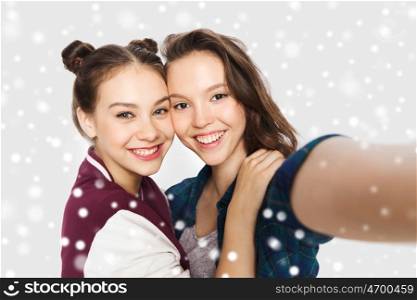 winter, christmas, people, teens and friendship concept - happy smiling pretty teenage girls or friends taking selfie over gray background and snow