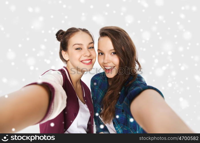 winter, christmas, people, teens and friendship concept - happy smiling pretty teenage girls or friends taking selfie over gray background and snow