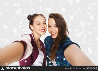 winter, christmas, people, teens and friendship concept - happy smiling pretty teenage girls or friends taking selfie over gray background and snow