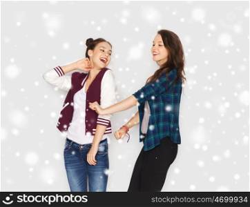 winter, christmas, people, teens and holidays concept - happy smiling pretty teenage girls or friends dancing over gray background and snow