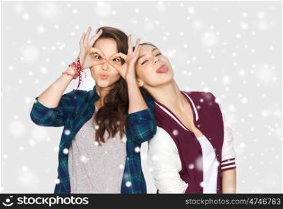 winter, christmas, people, teens and holidays concept - happy smiling pretty teenage girls or friends having fun and making faces over gray background and snow