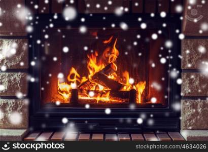 winter, christmas, warmth, fire and coziness concept - close up of burning fireplace at home with snow