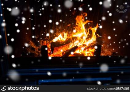 winter, christmas, warmth, fire and coziness concept - close up of burning fireplace with snow