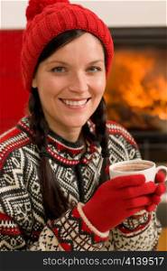 Winter christmas woman with hat and gloves drink by fireplace