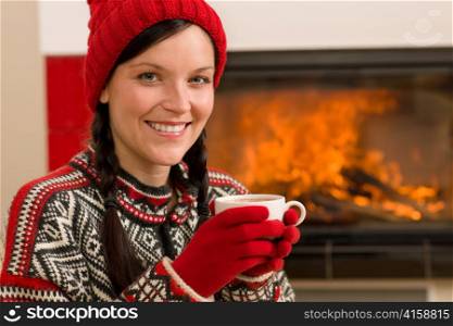 Winter christmas woman with hat and gloves drink by fireplace