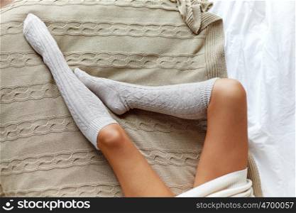 winter, clothes, fashion and people concept - close up of young woman legs in knee socks in bed at home