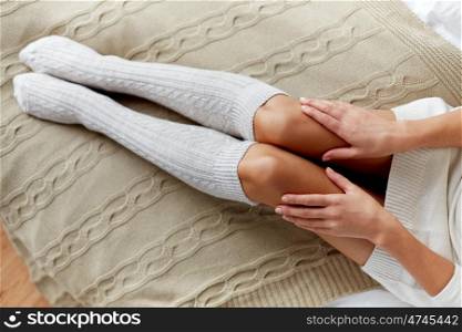 winter, clothes, fashion and people concept - close up of young woman legs in knee socks in bed at home