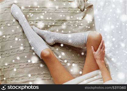 winter, clothes, fashion and people concept - close up of young woman legs in knee socks on bed over snow. close up of woman legs in winter knee socks on bed