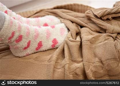 winter, comfort and people concept - woman or girl feet in socks and knitted plaid. woman or girl feet in socks and knitted plaid